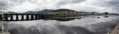 Vista panor  mica de la ria de Vicedo en Lugo con vistas del viejo puente y nubes reflejadas en el agua del r  o  en Galicia  verano de 2021