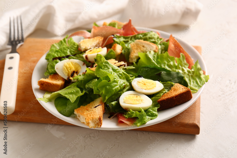 Plate of delicious salad with boiled eggs and jamon on white grunge background