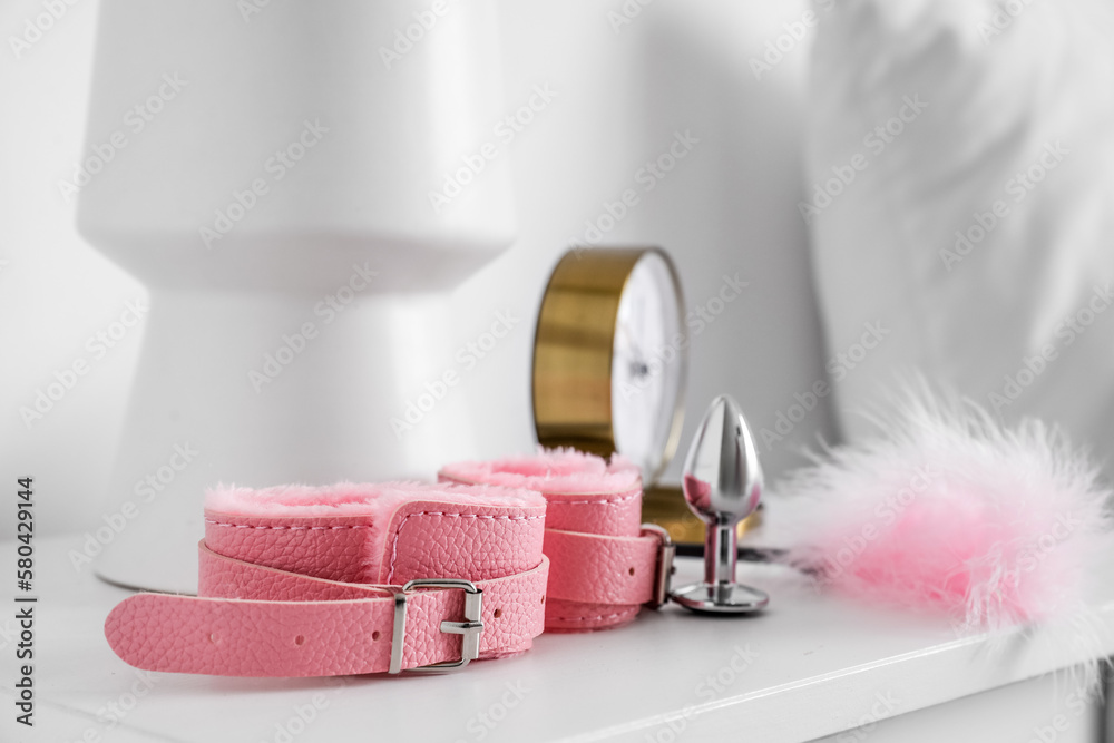Sex toys and alarm clock on bedside table in morning, closeup Sex toys and alarm clock on bedside table in morning, closeup