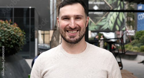 Young bearded man smiling outdoor. 