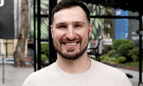 Young bearded man smiling outdoor. 