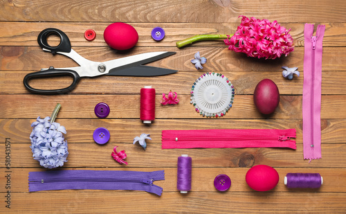 Sewing supplies with Easter eggs and flowers on wooden background