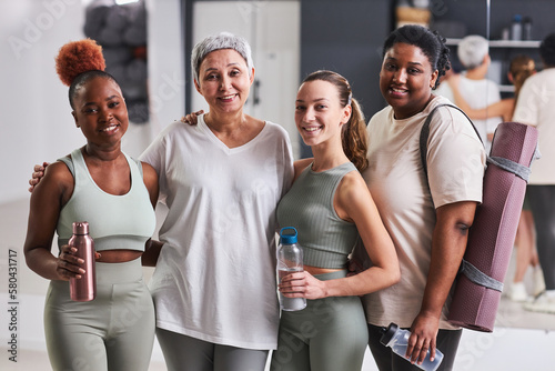 Portrait of group of women smiling at camera together standing in health club after sport training