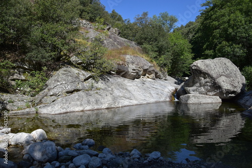 Ein natürlicher kleiner Badesee versteckt in der Natur, umrundet von Felsen und Sträuchern