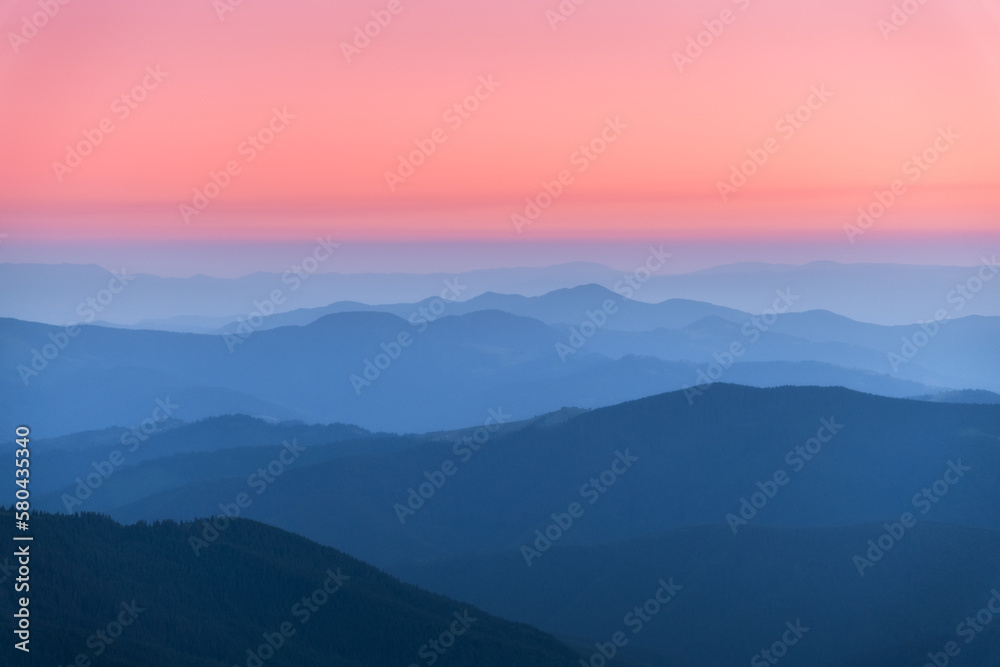 Amazing silhouettes of a mountains at colorful sunset in summer in Ukraine. Landscape with mountain ridges in fog, pink sky in the evening. Nature background. Hills at twilight. Scenery