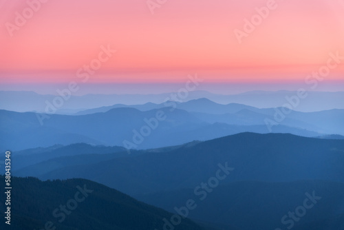 Amazing silhouettes of a mountains at colorful sunset in summer in Ukraine. Landscape with mountain ridges in fog  pink sky in the evening. Nature background. Hills at twilight. Scenery