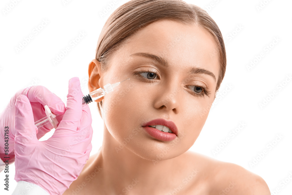 Young woman receiving filler injection in face against white background