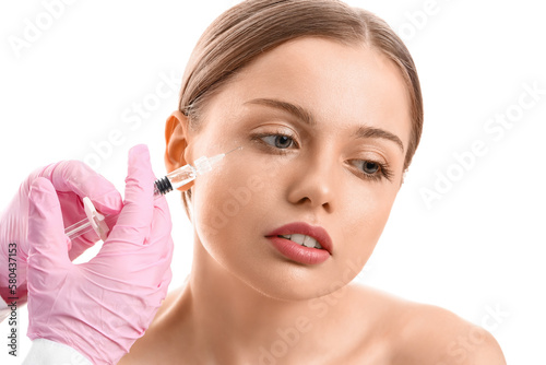 Young woman receiving filler injection in face against white background