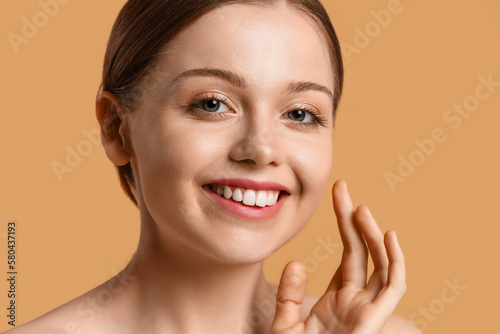 Pretty young woman with healthy skin on beige background