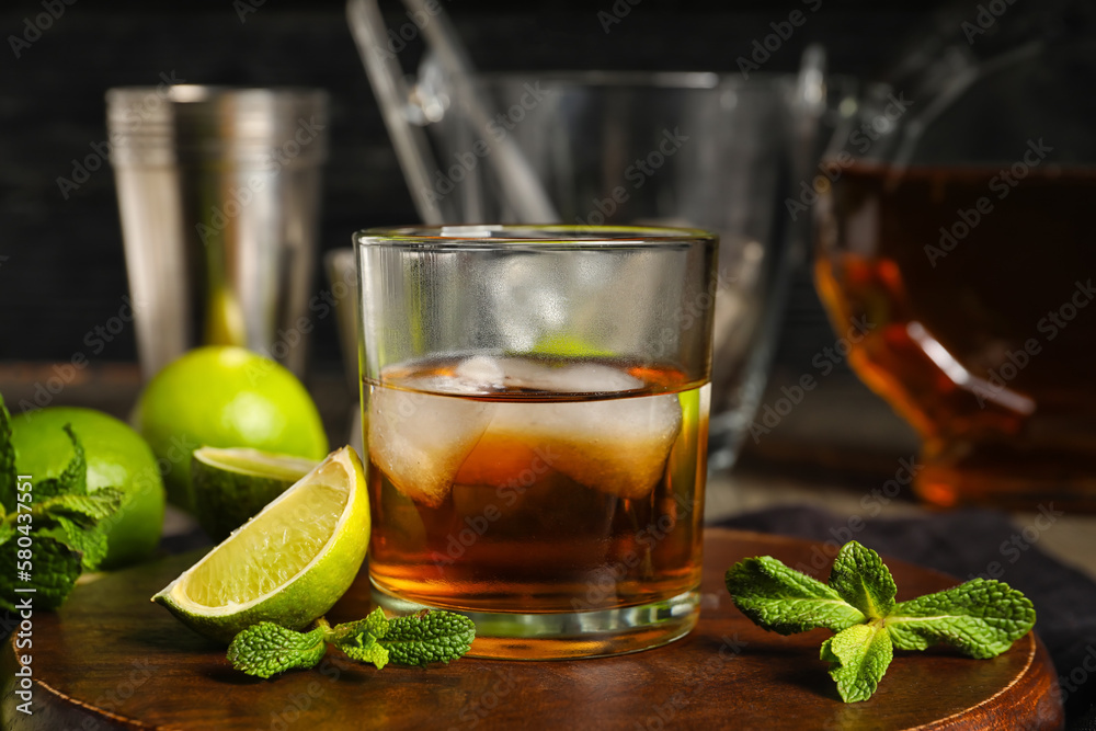 Glass of rum with ice, mint and lime on table Glass of rum with ice, mint and lime on table