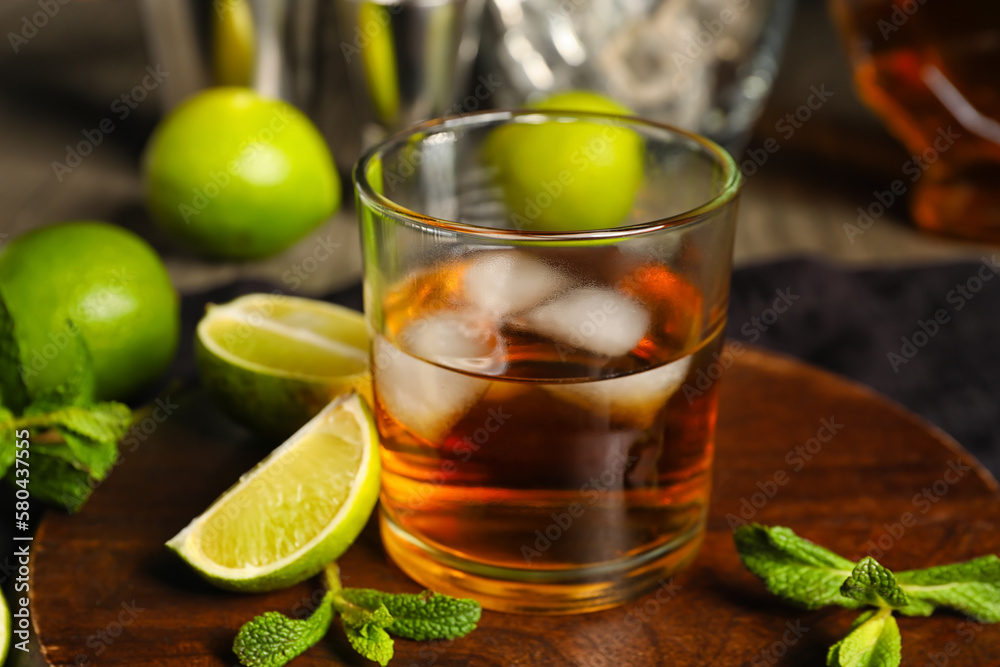 Glass of rum with ice, mint and lime on table Glass of rum with ice, mint and lime on table