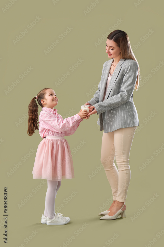 Cute little girl greeting her mother with gift on green background Cute little girl greeting her mother with gift on green background