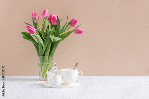Ceramic whites tea-set, cup and milk jug on the table with flowers . Place for text. Backdrop for tea branding or menu. 