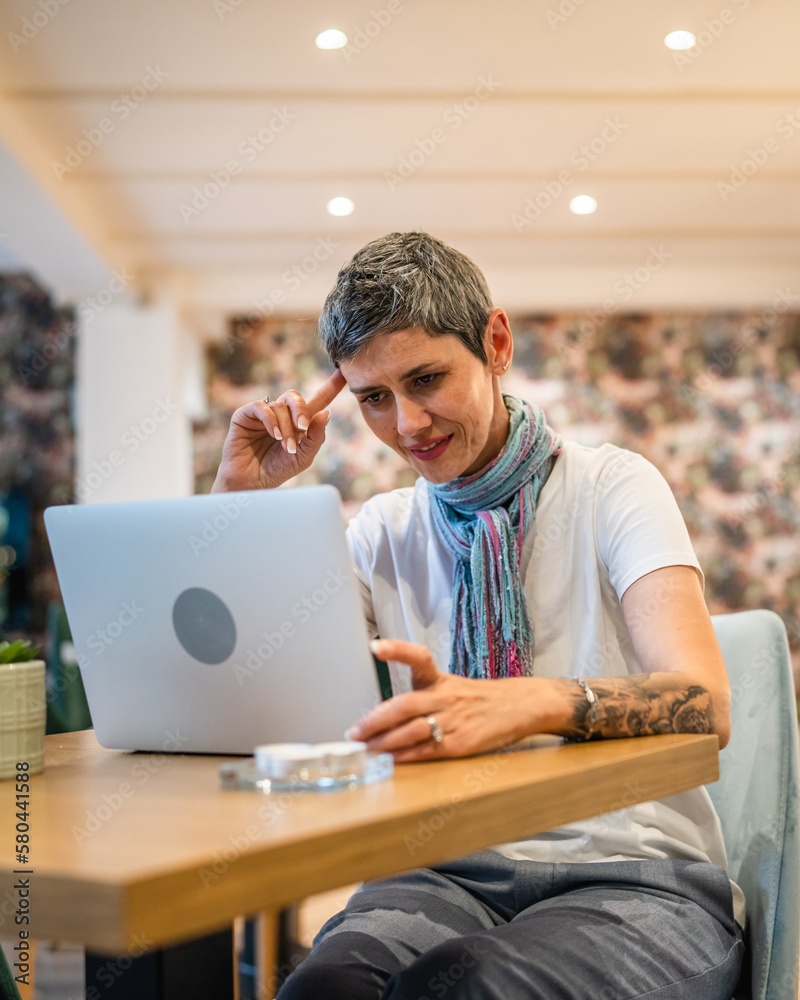 One woman mature adult senior female work on laptop at cafe One woman mature adult senior female work on laptop at cafe