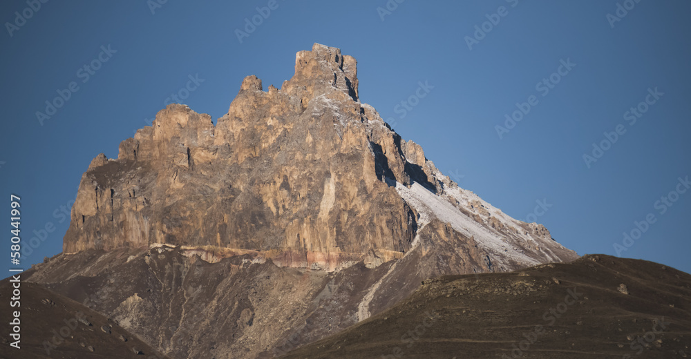 Rocky peak in the mountains with cliffs and rocky slopes with snow, autumn in the mountains
