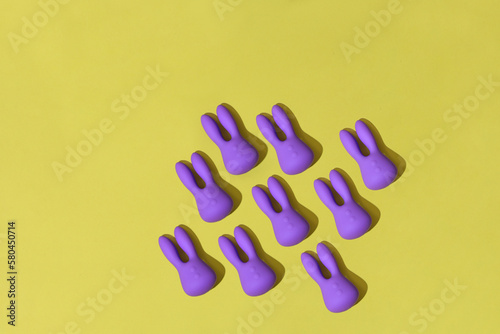 Many violet dildo vibrators for clitoris on yellow background. Sex toys for adult