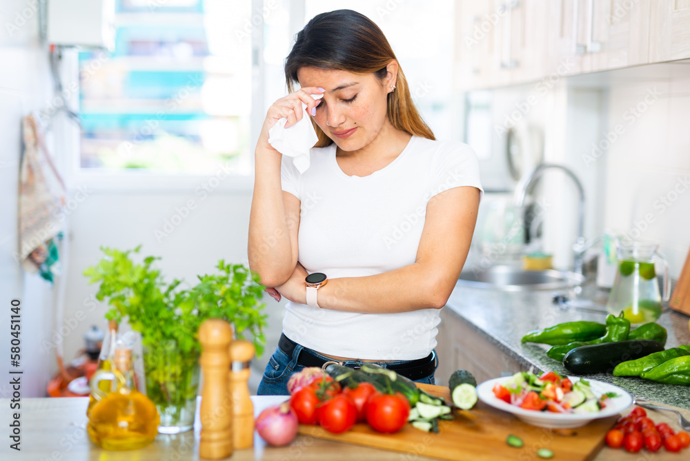 Portrait of adult sad latino woman tired of worries at kitchen