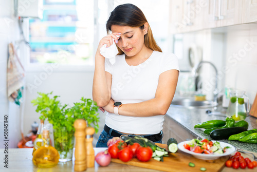 Portrait of adult sad latino woman tired of worries at kitchen