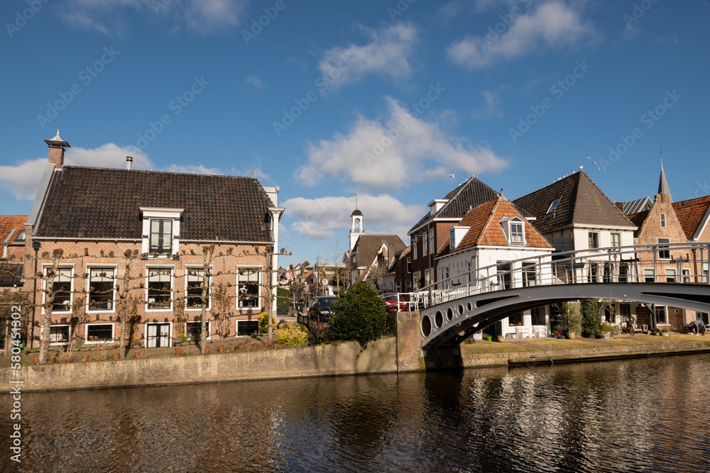 Bontebrug bridge at the turfmarkt with waterside residential houses on the edge of the river kleindiep waterway in Dokkum, Friesland, Netherlands Holland on sunny day. 
