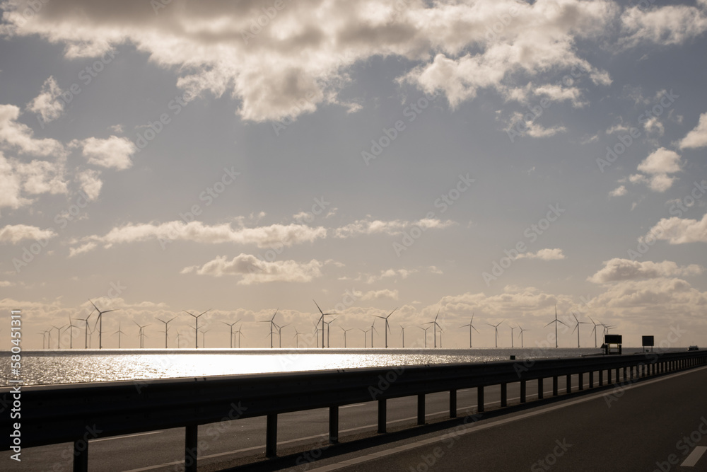 Windpark Fryslân offshore from Afsluitdijk highway. Dutch wind turbine farm generating clean sustainable renewable energy for Holland on clear sunny day. Netherlands eco power at sea water IJsselmeer Windpark Fryslân offshore from Afsluitdijk highway. Dutch wind turbine farm generating clean sustainable renewable energy for Holland on clear sunny day. Netherlands eco power at sea water IJsselmeer