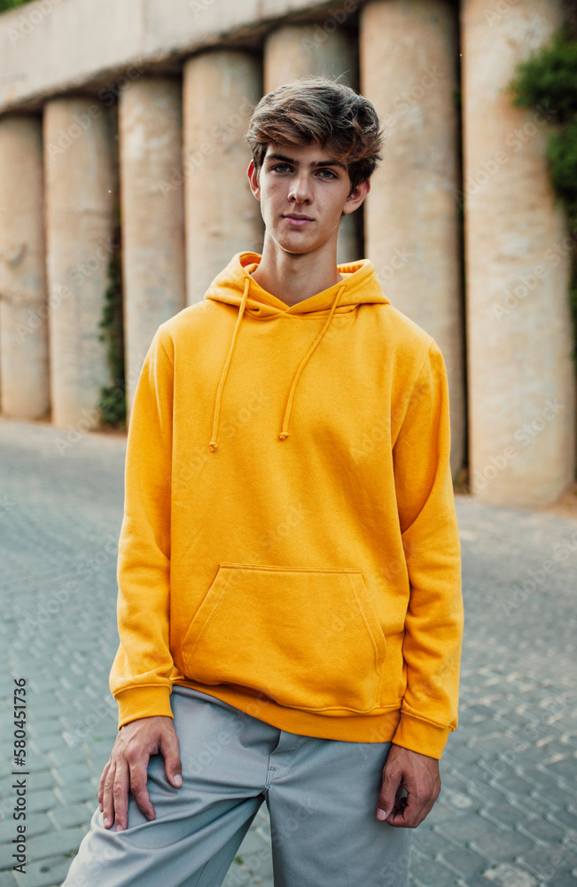 City portrait of handsome young guy wearing yellow blank hoodie or sweatshirt with space for your logo or design. Mockup for print