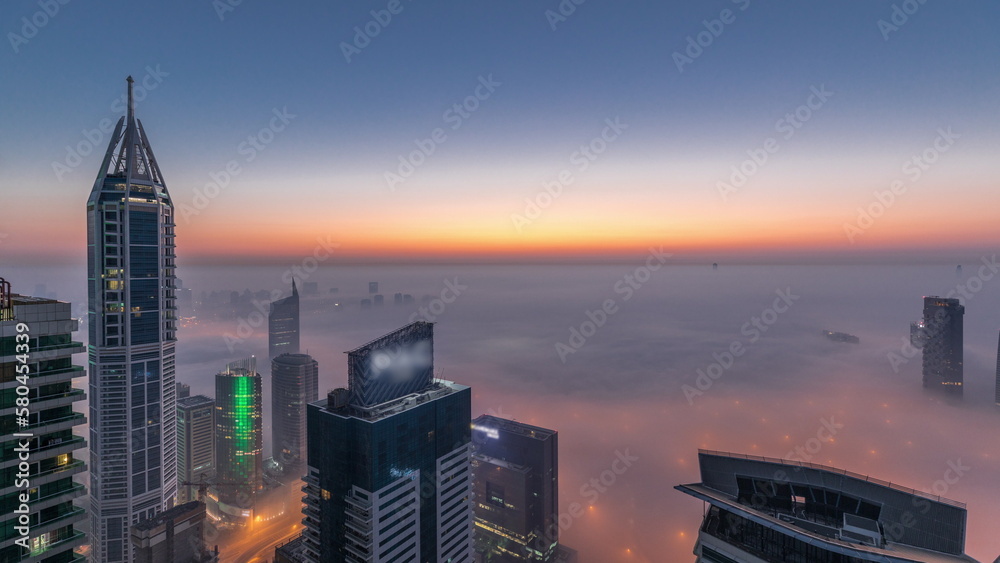 Rare early morning winter fog above the Dubai Marina skyline and skyscrapers lighted by street lights aerial night to day timelapse. - obrazy, fototapety, plakaty 