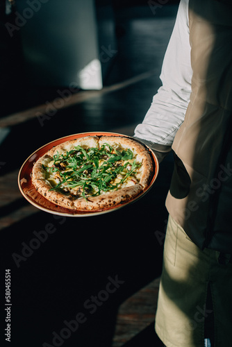 chef holding pizza with cheese