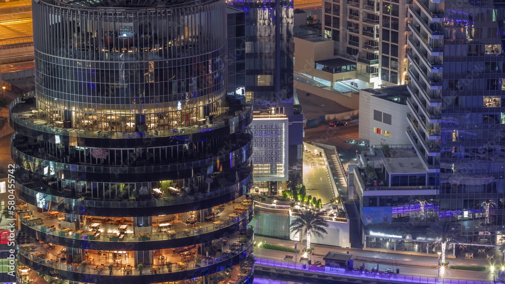 Dubai marina waterfront and building with different restaurants at each floor aerial all night timelapse.