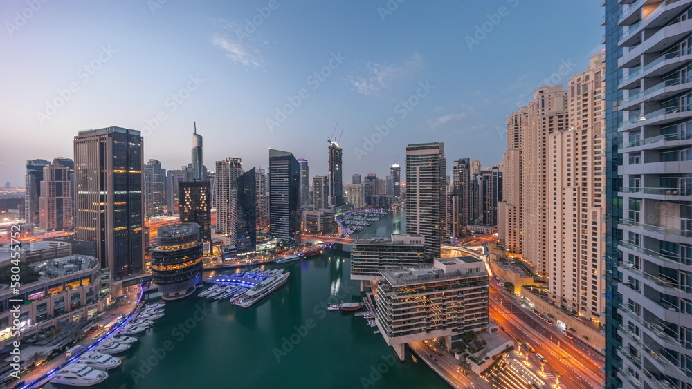 Aerial view to Dubai marina skyscrapers around canal with floating boats night to day timelapse