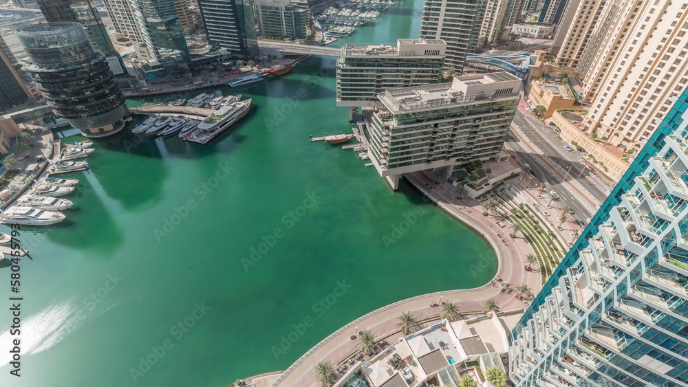 Aerial view to Dubai marina skyscrapers around canal with floating boats all day timelapse