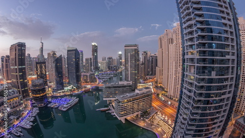 Aerial view to Dubai marina skyscrapers around canal with floating boats night to day timelapse