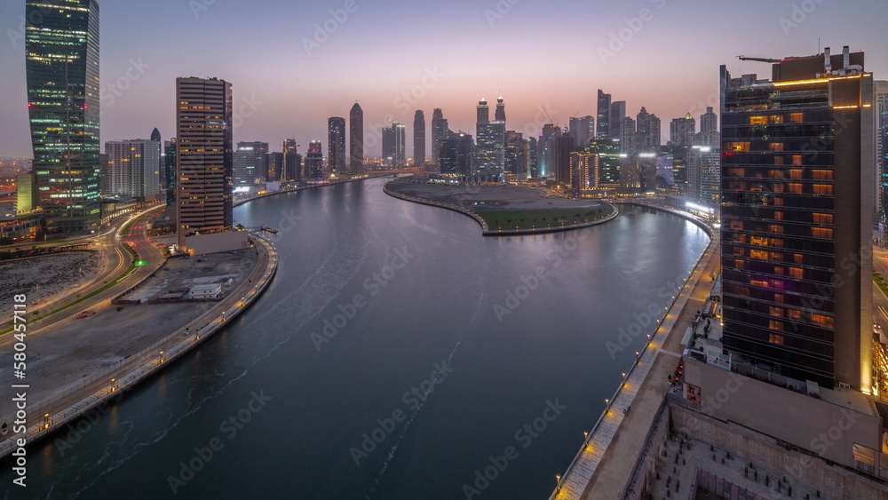Fototapeta premium Cityscape of skyscrapers in Dubai Business Bay with water canal aerial day to night timelapse