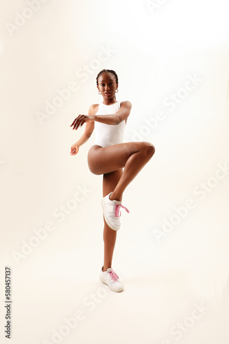 Young woman with perfect body dancing over white wall. Vertical mock-up.