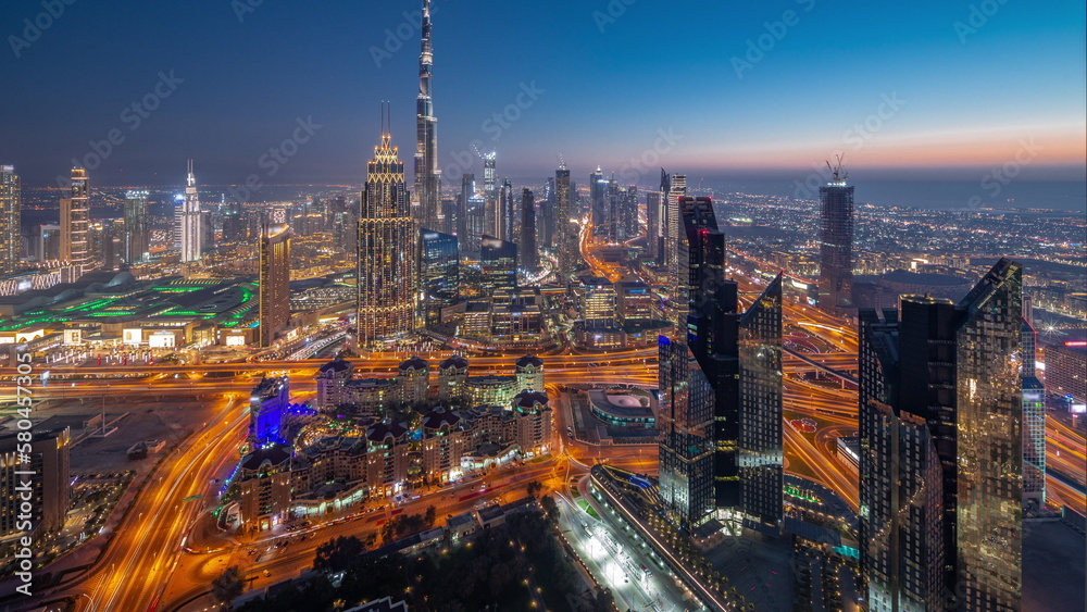 Naklejka premium Aerial view of tallest towers in Dubai Downtown skyline and highway day to night timelapse.