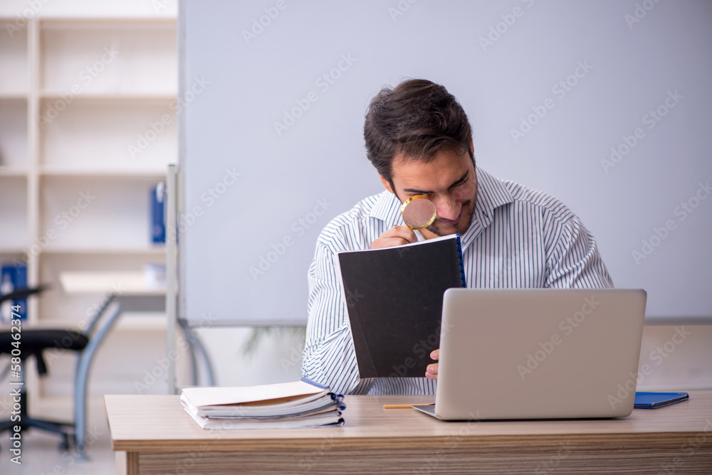 Young male teacher sitting in the classroom Young male teacher sitting in the classroom