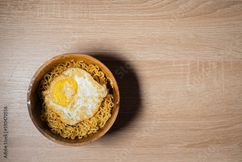 Flat Lay of Fried Noodles and Sunny-Side Up Egg on a Wooden Bowl and Wooden Table photo