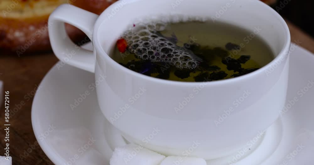 brewing green tea with hot boiled water in a white mug, a mug made of white glass with green tea is filled with boiling water brewing green tea with hot boiled water in a white mug, a mug made of white glass with green tea is filled with boiling water
