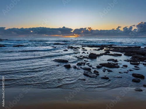 Summer sunrise at the seaside with clouds and rocks