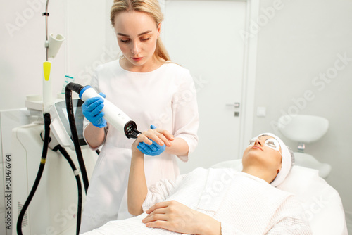 doctor cosmetologist makes laser cleaning of the skin on the arm of the patient with modern professional equipment