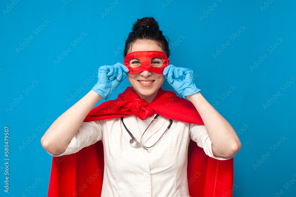 girl doctor in uniform in superman costume on blue background, female nurse  puts on superhero mask, healthcare concept Photos | Adobe Stock