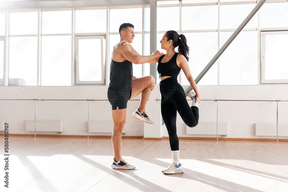 Fototapeta premium athletic couple in sportswear warm up in the gym in the morning, fitness girl and coach man go in for sports in training