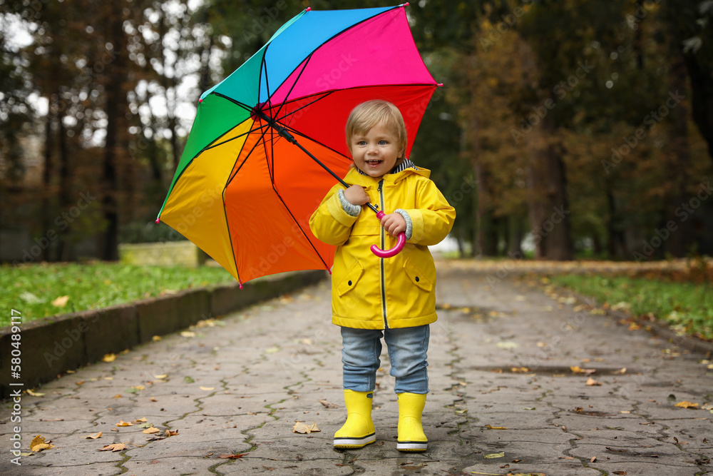 Obraz premium Little girl with colorful umbrella walking outdoors