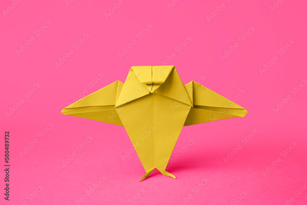 Origami art. Handmade green paper bird on pink background