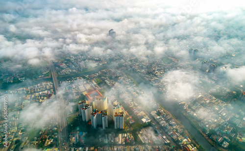 Aerial view of Saigon cityscape at morning with misty sky in Southern Vietnam. Urban development texture, transport infrastructure and green parks