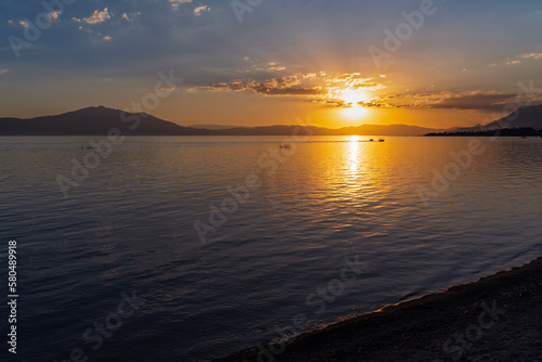 sun sets on lake chapala and mountains on horizon illuminating water in jalisco mexico