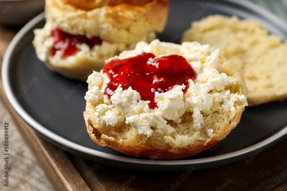 Freshly baked soda water scones with cranberry jam and butter on wooden table, closeup