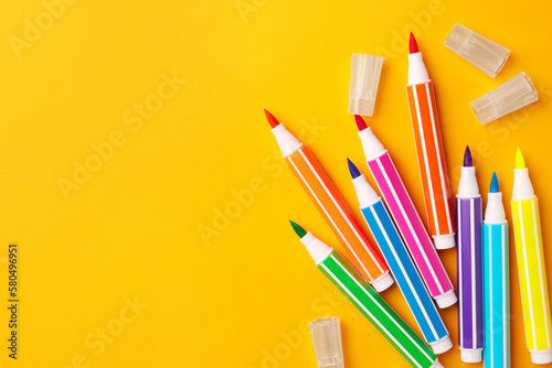 Many bright markers on yellow background, flat lay. Space for text