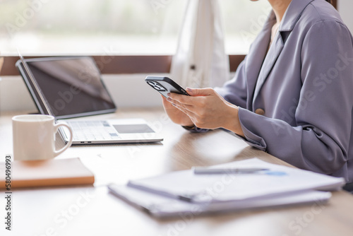 Happy Young Asian woman using laptop while working at home with documents. online documentation calculator to calculate the numbers, finance accounting office concept