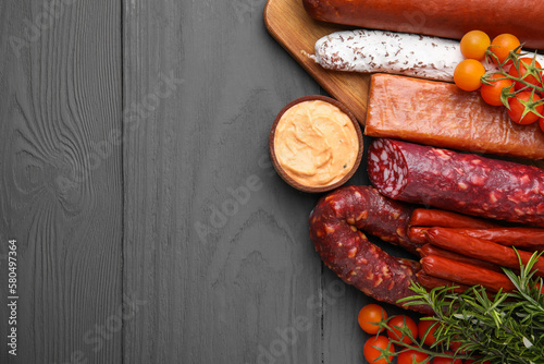 Different types of tasty sausages on grey wooden table, flat lay. Space for text