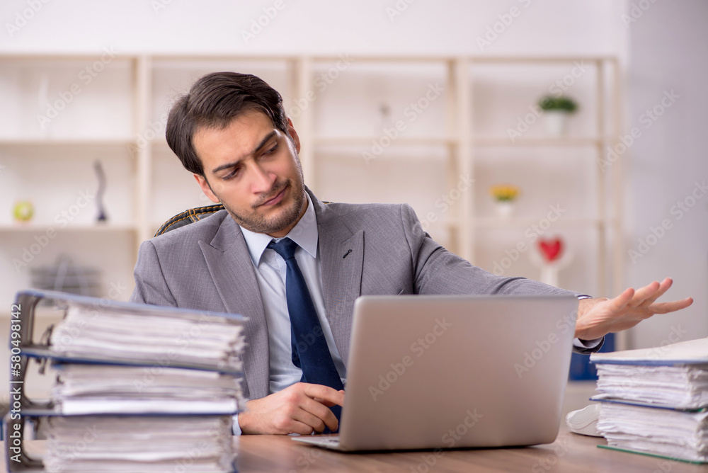 Young male employee and too much work in the office Young male employee and too much work in the office